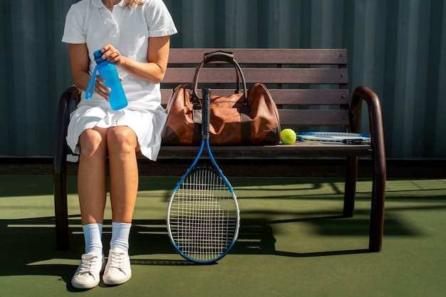 A tennis player sitting on a bench, reviewing a tournament schedule and making notes with a pen and paper. A water bottle and tennis racket are beside them.