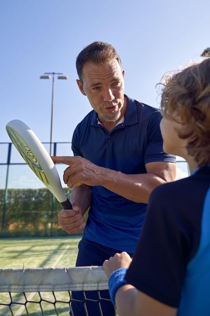 A tennis coach instructing a player on their serve technique, with close attention to grip and stance.