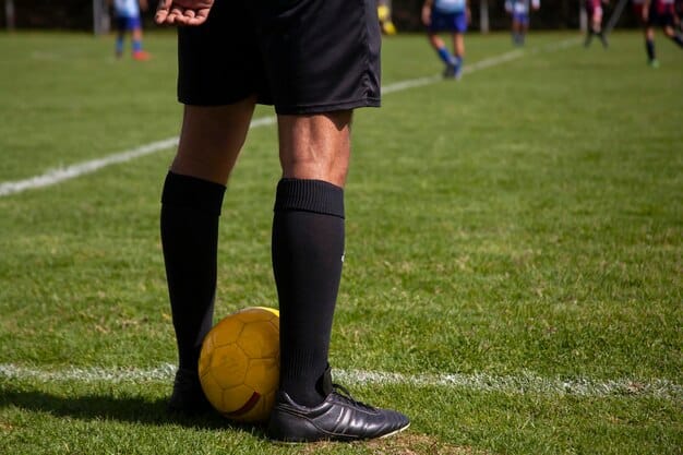 A close-up shot of a soccer player's legs in action during a Série A match in Brazil, showing the player dribbling the ball with focus and determination, and a stadium full of fans cheering in the background.