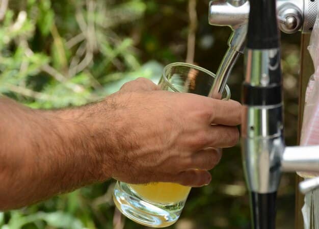 A close-up of an eco-friendly water station at a cycling event in São Paulo, Brazil. The water bottles are biodegradable, and there are signs promoting water conservation. Volunteers are assisting the cyclists, showcasing a sense of community and environmental responsibility.