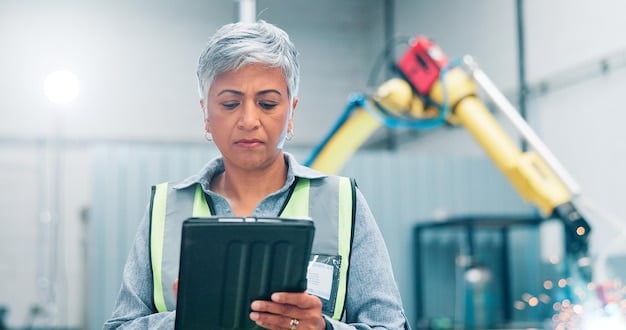 A factory worker using a tablet to monitor the performance of a robotic arm. The tablet displays real-time data and alerts, allowing the worker to quickly identify and address any issues.