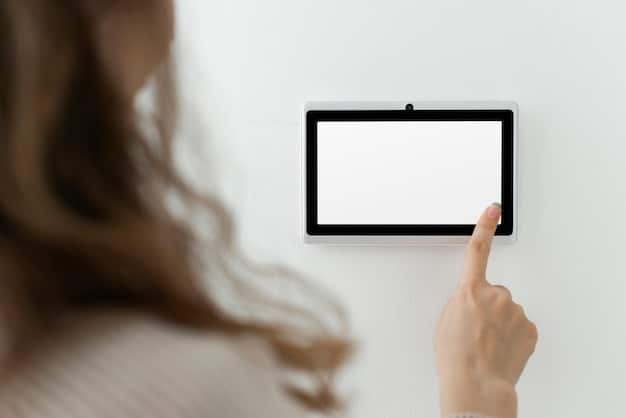 A close-up shot of a smart thermostat mounted on a wall, with a hand adjusting the temperature. The thermostat has a sleek, modern design with a clear digital display.