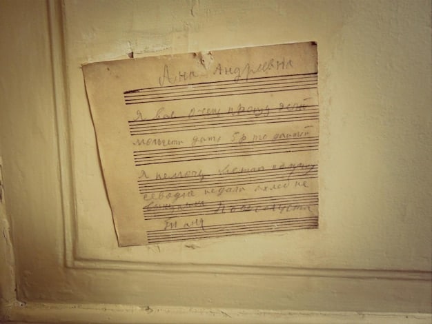 An antique sheet music with yellowed pages, displaying handwritten musical notes and faded ink. A quill pen rests on top of the sheet, near a partially visible handwritten signature that reads 