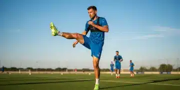 Jogador de futebol realizando alongamento dinâmico em campo verde